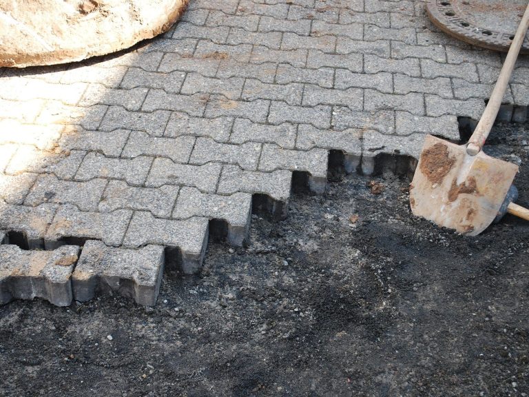Gleichmäßig verlegte Pflastersteine auf einem ebenen Untergrund mit einer Schaufel.